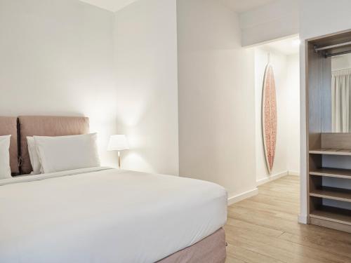 a white bedroom with a white bed and a window at NLH Mati Seafront - Neighborhood Lifestyle Hotels in Mati