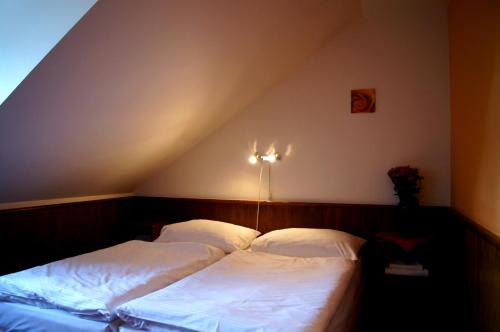 a bedroom with two beds with white sheets at Hotel Floret in Pruhonice