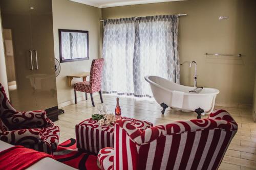 baño con bañera, sofá y silla en The Daughters Guest House, en Bethlehem