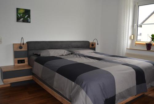 a bedroom with a bed with a black and gray blanket at Fewo Bauer in Oberkotzau