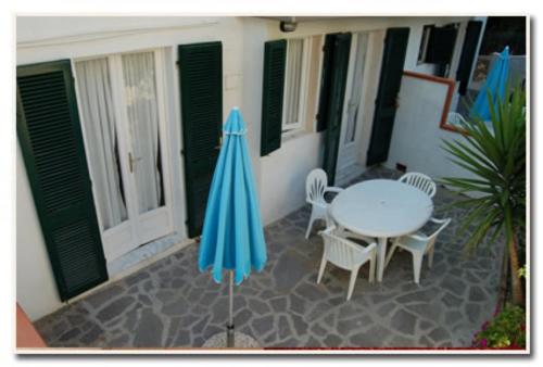 a patio with a table and chairs and an umbrella at Appartamenti Villa Miramare in Capoliveri