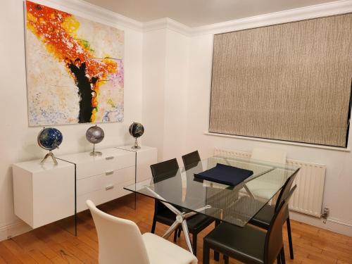 a dining room with a glass table and chairs at Garland Stylish 2 Bedroom Apartment A Minute Walk From Station in London