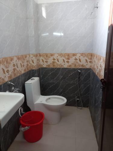 a bathroom with a toilet and a sink and a bucket at Metro Regency - Near Hazratganj & Charbagh in Lucknow