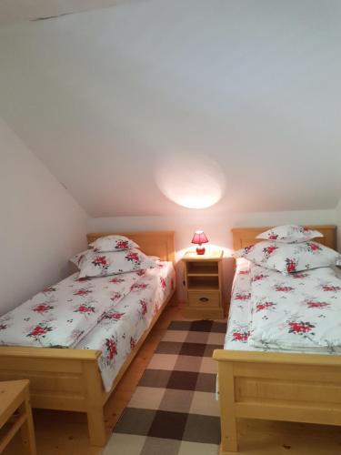 a bedroom with two beds and a table with a lamp at Szálka Kulcsosház in Lunca de Sus