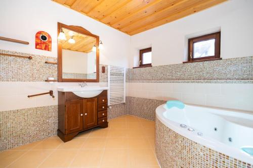 ein Badezimmer mit einer Badewanne, einem Waschbecken und einem Spiegel in der Unterkunft Očarujúci drevený dom v prírodnom prostredí in Kordíky