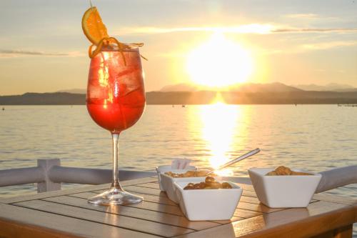 a drink with an orange slice on a table near the water at Hotel Flaminia in Sirmione