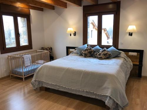 a bedroom with a large bed and two windows at Maison Cerdagne in Bourg-Madame