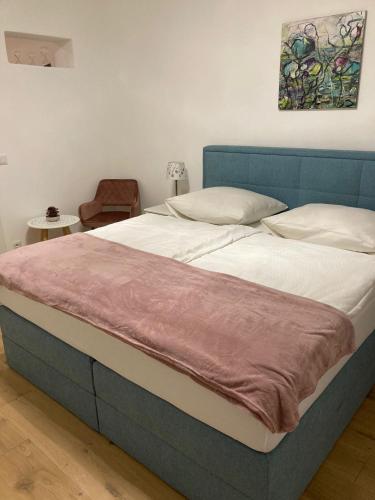 ein großes Bett mit blauem Kopfteil in einem Schlafzimmer in der Unterkunft Altes Bürgerhaus in Dürnstein