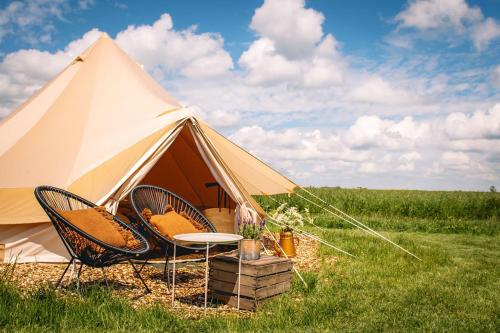 a tent with chairs and a table in a field at Smuk Lytse Bell Tent in Echtenerbrug