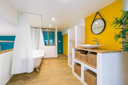 een badkamer met een bad, een wastafel en een spiegel bij Le Patio - SRLoc in Dijon