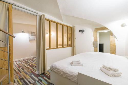 een slaapkamer met een wit bed en een raam bij Le Patio - SRLoc in Dijon