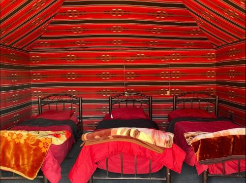 ワディ・ラムにあるWadi Rum Pyramids Campの赤い部屋にベッドが4台ある部屋
