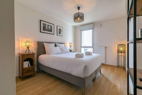 une chambre avec un grand lit blanc et une fenêtre dans l'établissement Le Carrousel, à Dijon