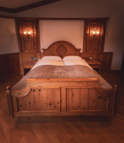 a large wooden bed in a bedroom with wooden cabinets at Hotel-Restaurant Kreuzberghof Tagungs- und Veranstaltungshotel in Tiefenbach
