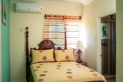 a bedroom with a bed with a window and a bed sidx sidx sidx at Lovely Ensuite Getaway with Pool in Ocho Rios