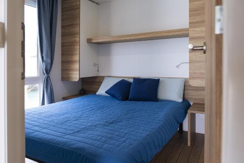 a bedroom with a bed with blue sheets and a window at Houseboat Floatart Experience Bisceglie in Bisceglie