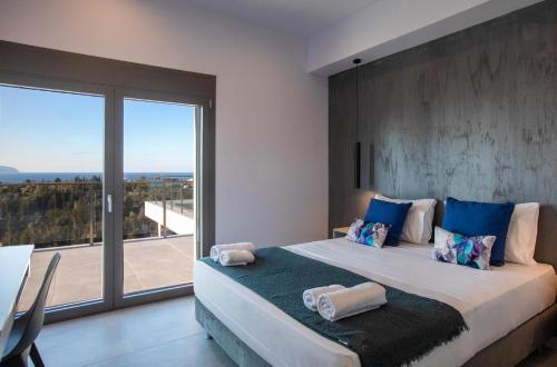 a bedroom with a large bed with a large window at Exclusive Villa Petalouda in Ratzaklíon