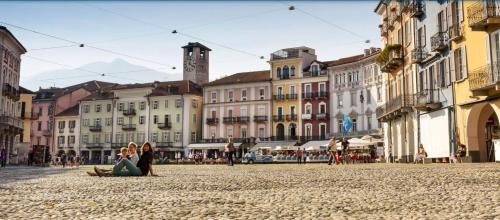 a group of people sitting on a street in a city at Villa Art'è in Locarno