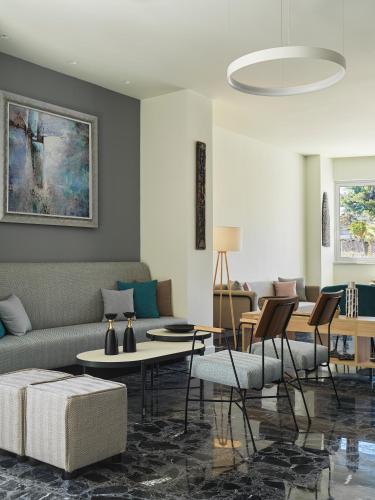 a living room with a couch and tables and chairs at NLH Mati Seafront - Neighborhood Lifestyle Hotels in Mati