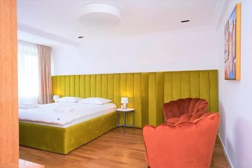 a bedroom with a bed and a red chair at Hotel Glory in Oradea