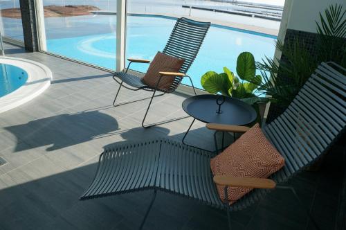 two chairs and a table next to a swimming pool at Best Western Hotel Corallen in Oskarshamn