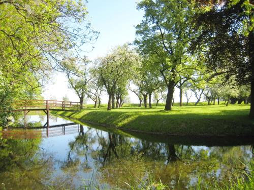 a river in a park with trees and a bridge at Hotel Am Markt Nordenham in Nordenham