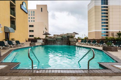 a swimming pool at a hotel with chairs and a fountain at Days Inn by Wyndham Virginia Beach At The Beach in Virginia Beach