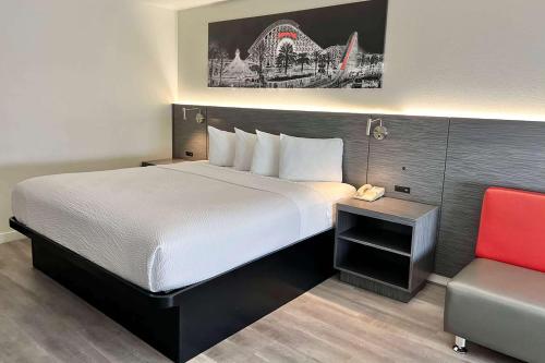 a hotel room with a bed and a red chair at Ramada by Wyndham Anaheim Convention Center in Anaheim