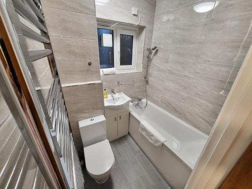 La salle de bains est pourvue de toilettes, d'une baignoire et d'un lavabo. dans l'établissement Garland Contemporary Central London Apartment, à Londres
