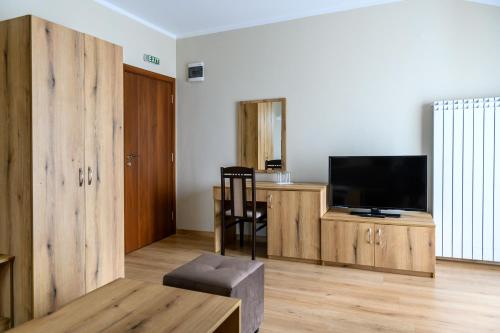 a living room with a television and a wooden cabinet at Семеен хотел При Вергил in Sapareva Banya
