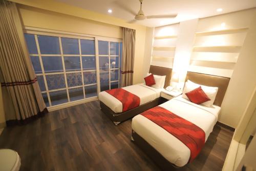 a hotel room with two beds and a large window at Hotel Picasso Prive Naraina Delhi - Couple Friendly Local IDs Accepted in New Delhi