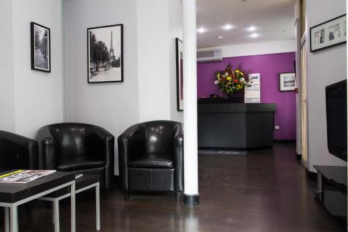 une salle d'attente avec des chaises noires et des murs violets dans l'établissement Hotel du Chemin Vert, à Paris