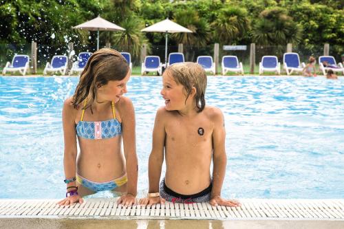 dos jovencitas parados en el borde de una piscina en Belambra Clubs Seignosse Les Estagnots en Seignosse