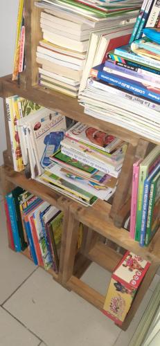a book shelf with a pile of books at LA P'TITE MAISON in Charleroi