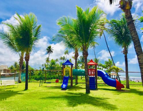 un parque infantil con palmeras y un tobogán en Paraíso dos corais Pe na areia en Guarajuba