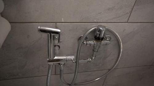 a shower with a hose attached to a wall at Comfortable stay in Shirley, Solihull - Room 3 in Olton