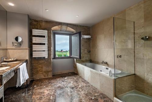 Un baño con bañera, lavabo y ventana. en CoolRooms Palacio de Luces, en Luces