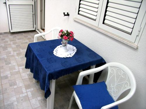 Una mesa azul con un jarrón de flores. en Apartments Vidović, en Vodice