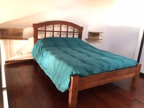 a bed with a green comforter in a room at Loft 5ta sección Mendoza in Mendoza