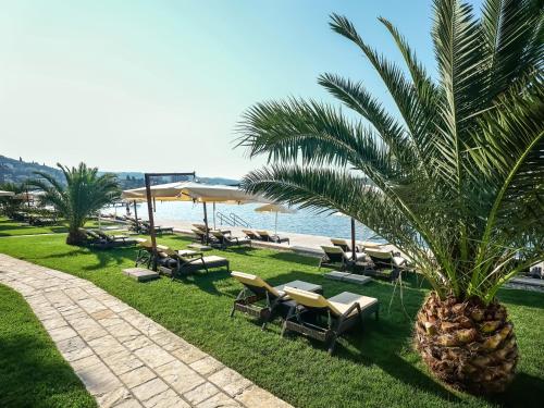 a resort with a palm tree and lounge chairs and the beach at Hotel Slovenija - Terme & Wellness LifeClass in Portorož