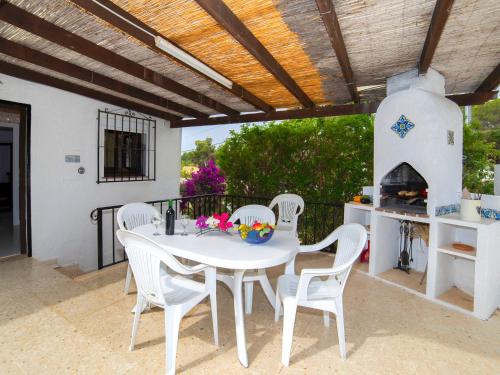 einen weißen Tisch und Stühle auf einer Terrasse mit Kamin in der Unterkunft Holiday Home La Cigarra by Interhome in Calpe