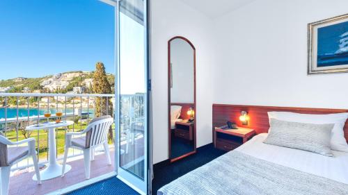 a hotel room with a bed and a balcony at Hotel Komodor in Dubrovnik
