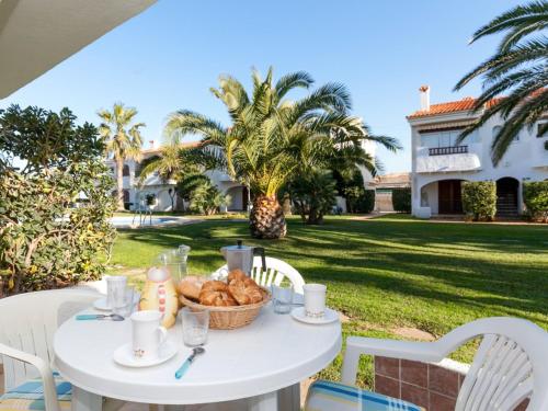 a white table with a basket of bread on a yard at Apartment Nueva Playa-1 by Interhome in Les Deveses	