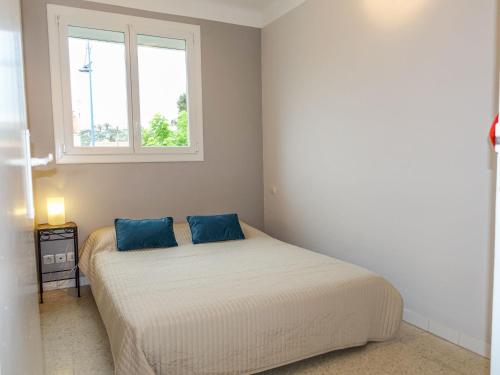ein Schlafzimmer mit einem Bett mit zwei blauen Kissen in der Unterkunft Apartment Idgil by Interhome in Saint Pierre La Mer