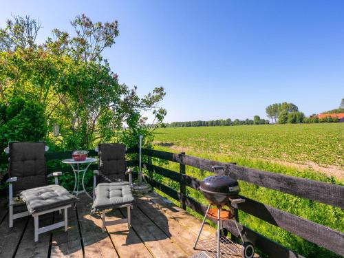 a patio with two chairs and a grill and a field at Holiday Home Tuinzicht by Interhome in Zuid-Beijerland