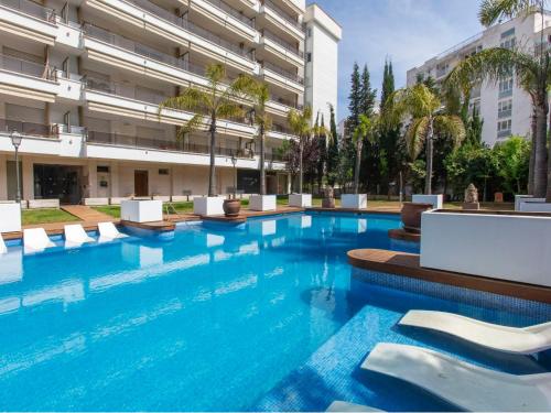 una gran piscina con sillas blancas y un edificio en Apartment Fenals Beach by Interhome, en Lloret de Mar