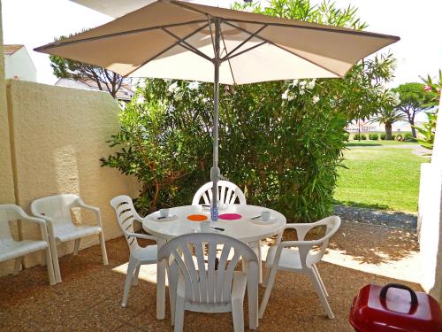 een witte tafel en stoelen met een parasol bij Apartment Antigua by Interhome in Le Barcarès