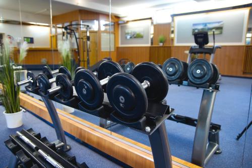 a gym with a rack of dumbbells in a room at AVALON Hotelpark Königshof in Königslutter am Elm