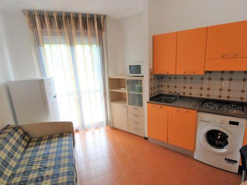 una cucina con armadi arancioni e lavatrice di Apartment Simma-11 by Interhome a Bibione