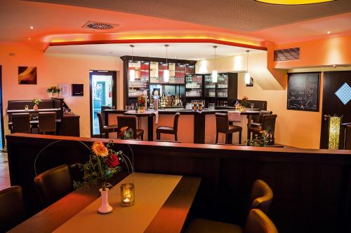 a restaurant with a bar with tables and chairs at AVALON Hotelpark Königshof in Königslutter am Elm